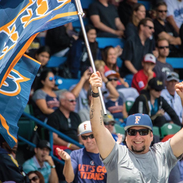 Cal State Fullerton fan waving a Titans flag at a baseball game